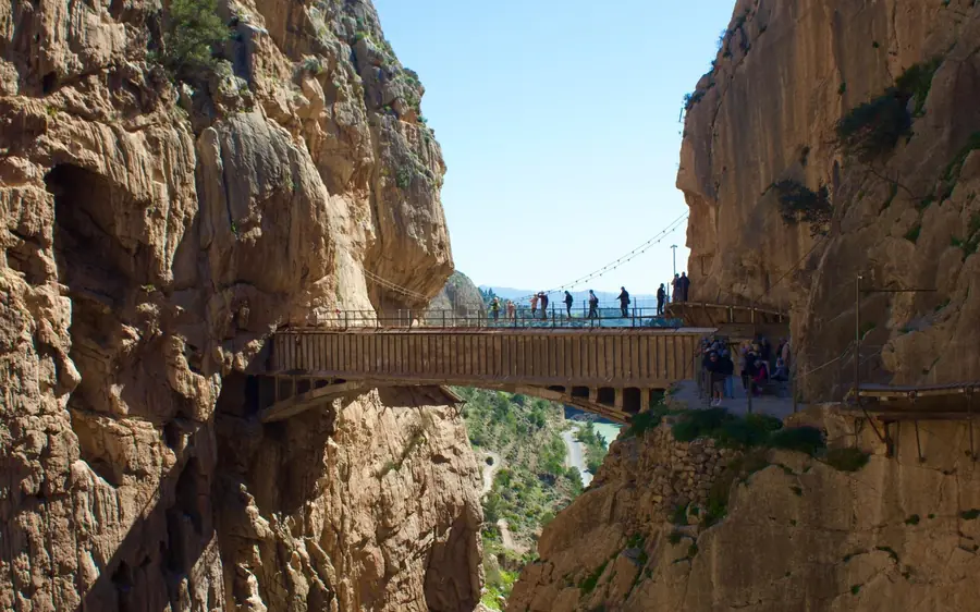 Visitors crossing a metal section of the Caminito del Rey path