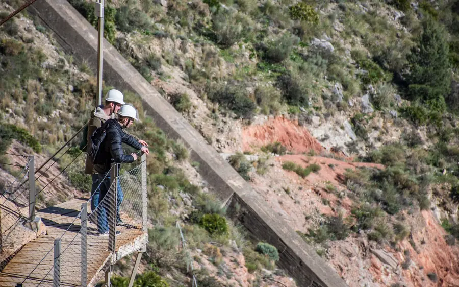 A guide pointing out the old path below the modern Caminito del Rey walkway